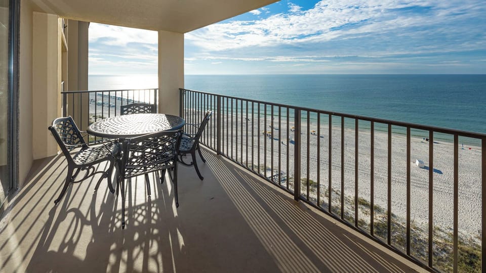 A round table with metal chairs overlooks the tranquil beachfront, inviting guests to enjoy the serene coastal view