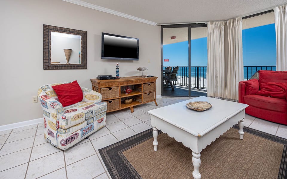 Relax in the inviting living area, featuring colorful seating and a view of the beach through expansive sliding doors