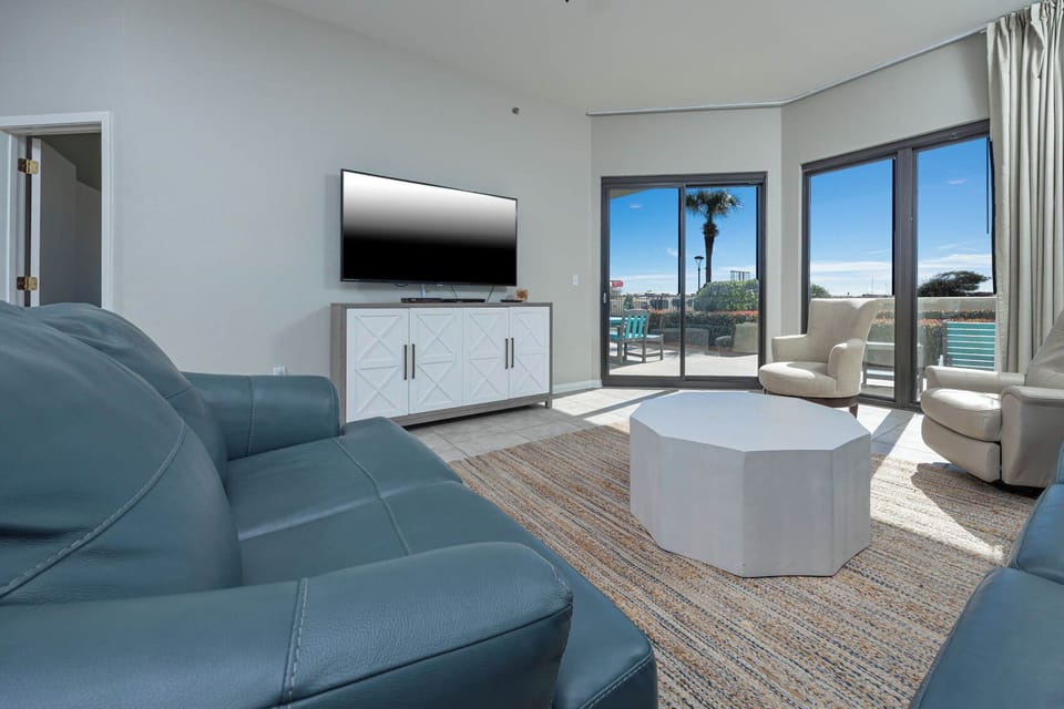 Cozy living area features a blue sofa with queen sleeper, modern coffee table, and large windows to the outdoor patio