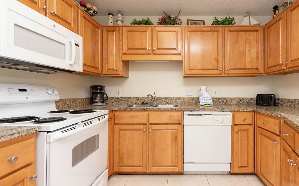 The kitchen features warm wooden cabinetry, granite countertops, and essential appliances for convenient meal preparation