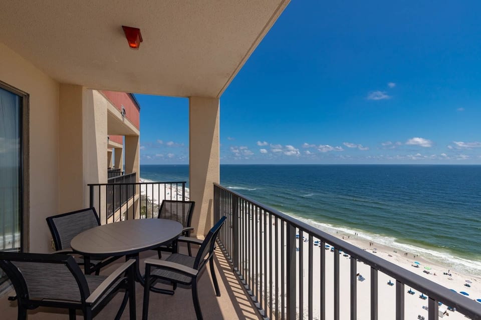 Enjoy a relaxing moment on the balcony with a table and chairs, overlooking the beach and vibrant blue waters