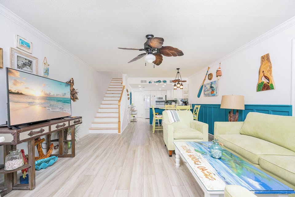 This living area features a large TV, bright green seating, and coastal decor, creating a cheerful atmosphere for relaxation