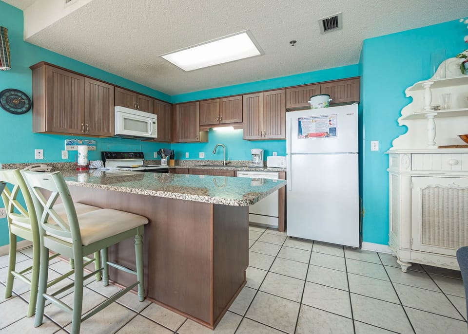 Bright turquoise walls complement the granite countertops and wood cabinetry in this inviting kitchen with bar seating