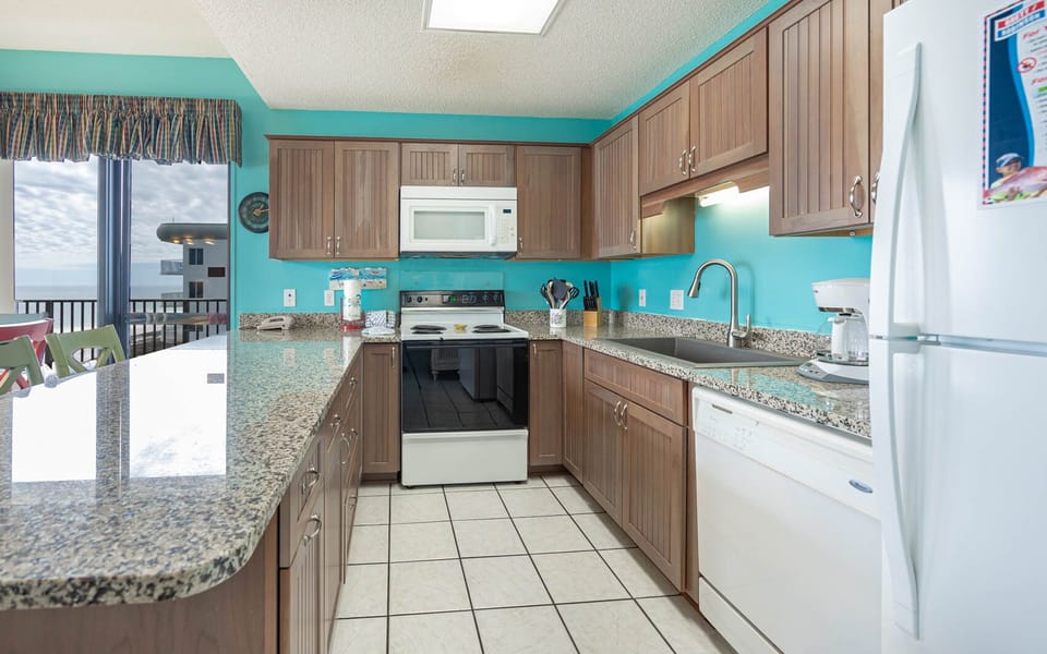 The kitchen features granite countertops, a breakfast bar, ample prep space, and beach front views