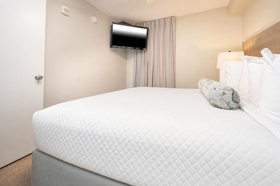 Rest comfortably in this bedroom featuring a plush king bed, soft linens, and a mounted TV for your entertainment