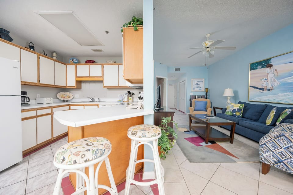 The inviting living area features a blue sofa with colorful pillows, a coffee table, and a breakfast bar with stylish stools