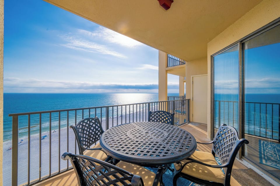 Enjoy the tranquil beachfront view from the private balcony, featuring a round table and comfortable seating for relaxation