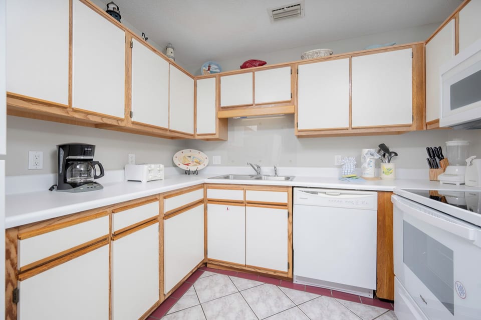 Fully-equipped kitchen featuring white cabinetry, a coffee maker, and a clean countertop for meal preparation