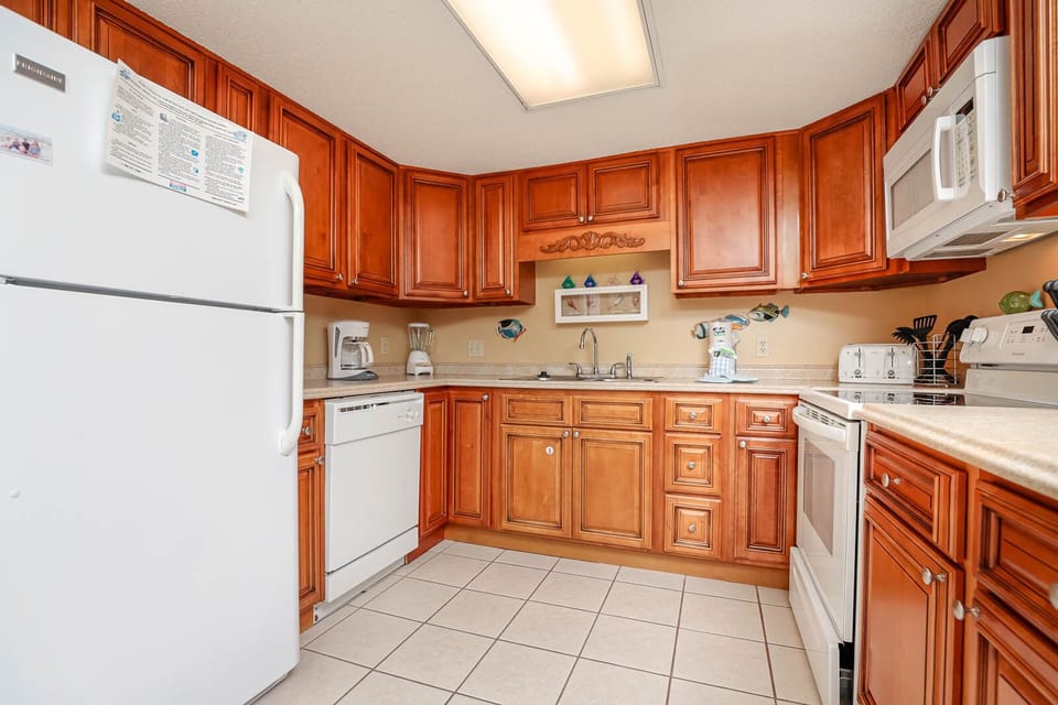 The kitchen features warm wood cabinetry, white appliances, and a cozy layout with ample counter space for meal preparation