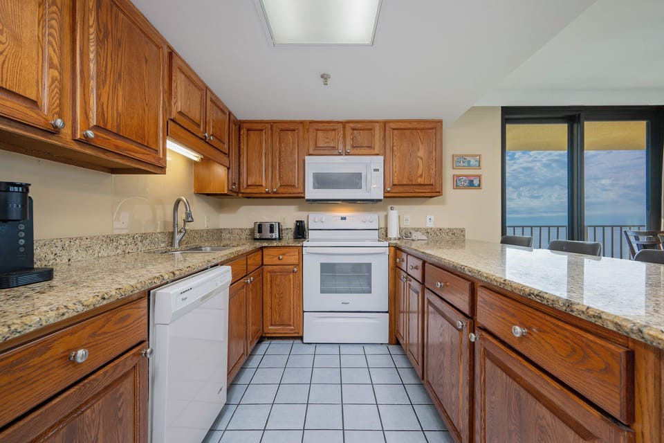 Kitchen featuring wooden cabinetry, granite countertops, and a view of the beach through large windows