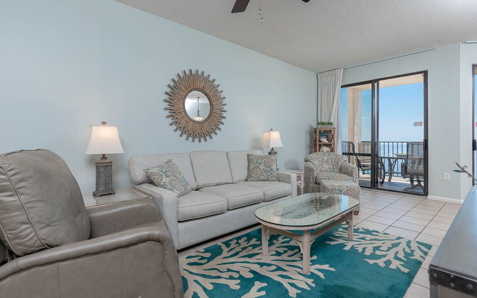 Relax in the inviting living area featuring a sofa with queen sleeper, coastal decor, and beachfront balcony access
