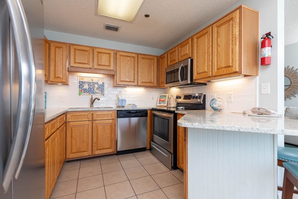Cook and gather in this inviting kitchen featuring wood cabinetry with stylish slighting and stainless appliances