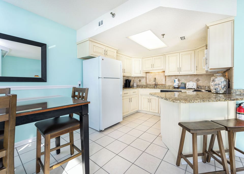 Cream cabinetry and granite counters create a kitchen where breakfast chatter fills the air