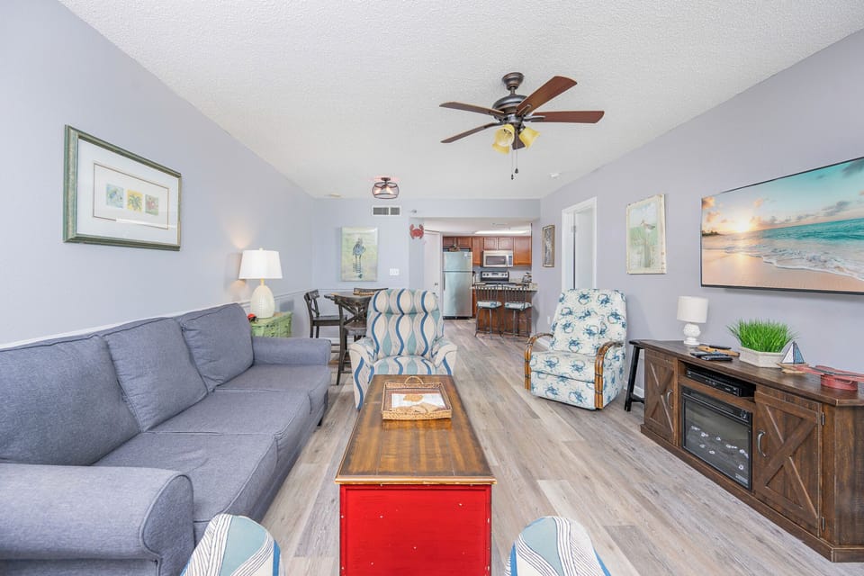 Spacious living area with comfortable seating, a rustic coffee table, and a view into the kitchen