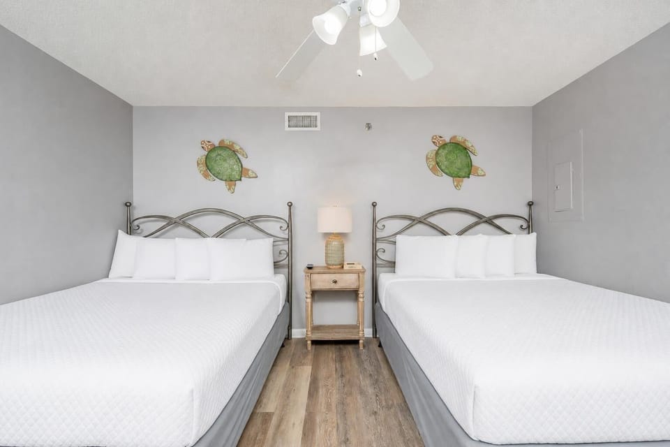 Cheerful guest room featuring two double beds, turtle decor, and a nightstand with a lamp
