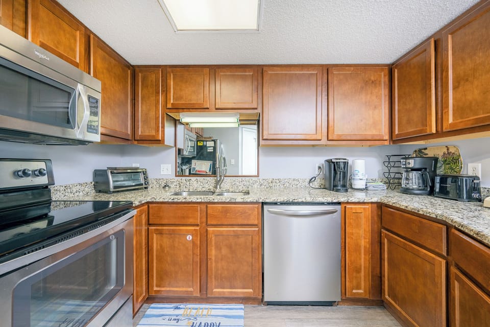 Prepare meals in this inviting kitchen featuring granite countertops, stainless appliances, and wooden cabinetry
