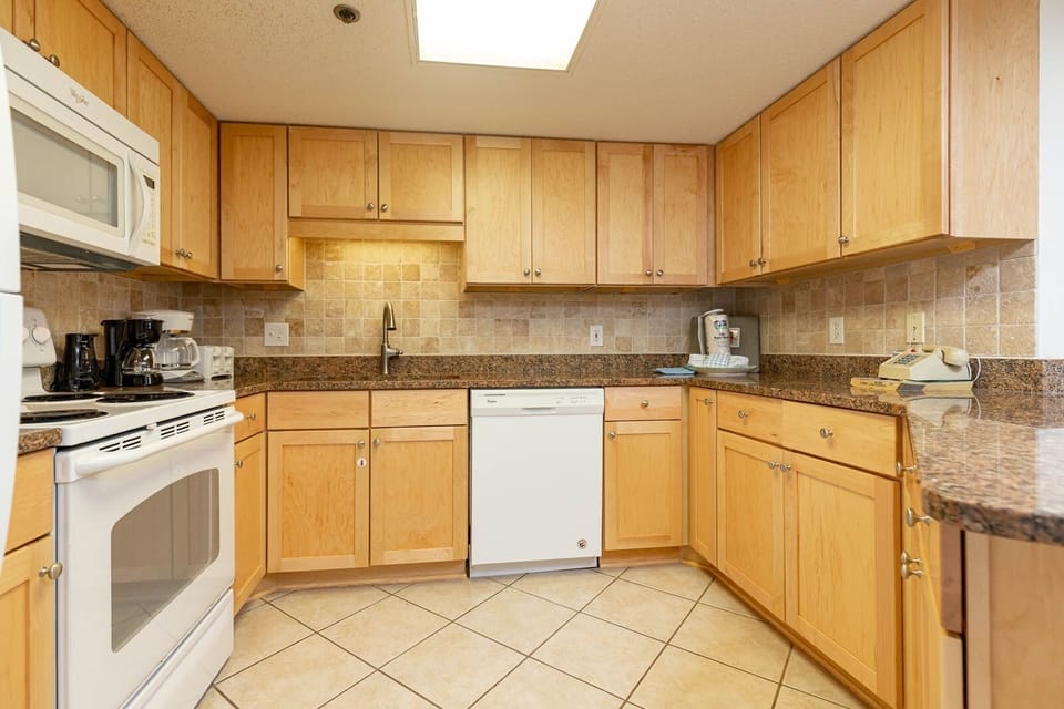 Prepare meals in the spacious kitchen featuring wood cabinets, granite countertops, and white appliances