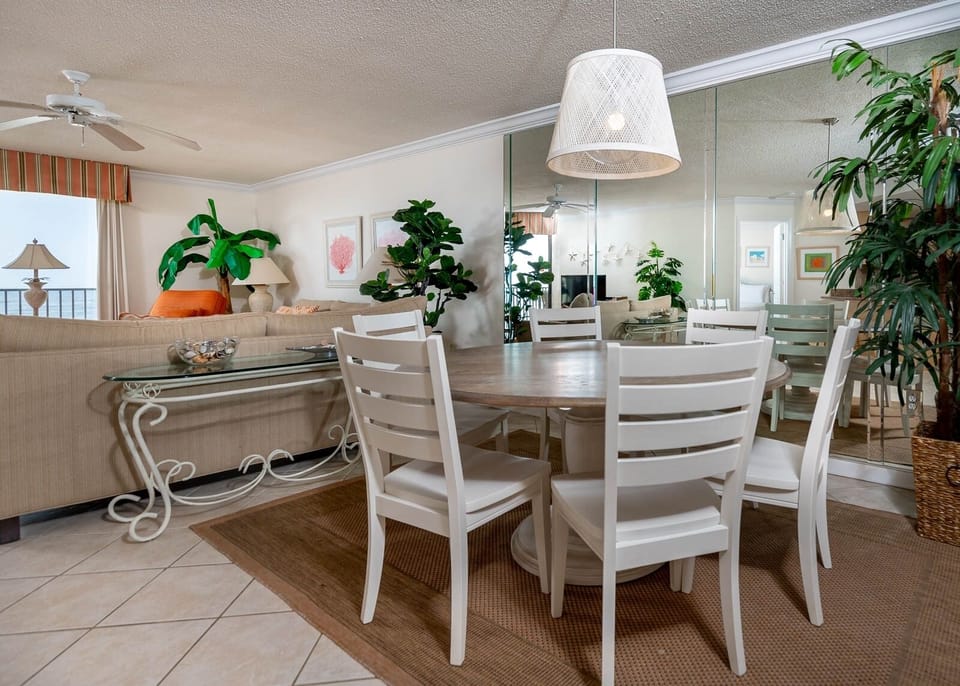 Gather around the round dining table surrounded by greenery and enjoy the inviting living space with beach views