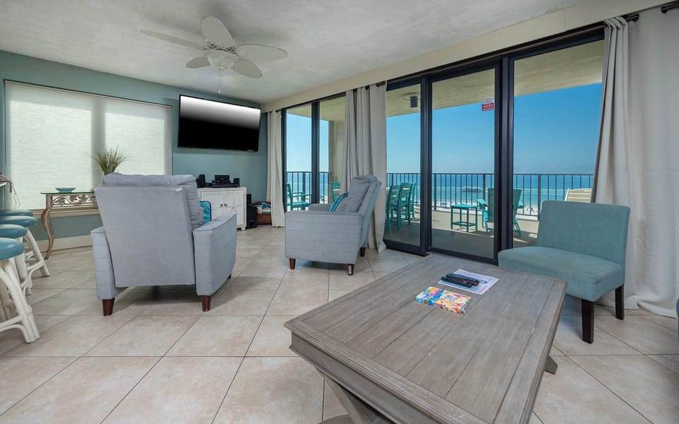 This living area features cozy seating, a queen sofa-sleeper, large TV, and a breathtaking view of the beach