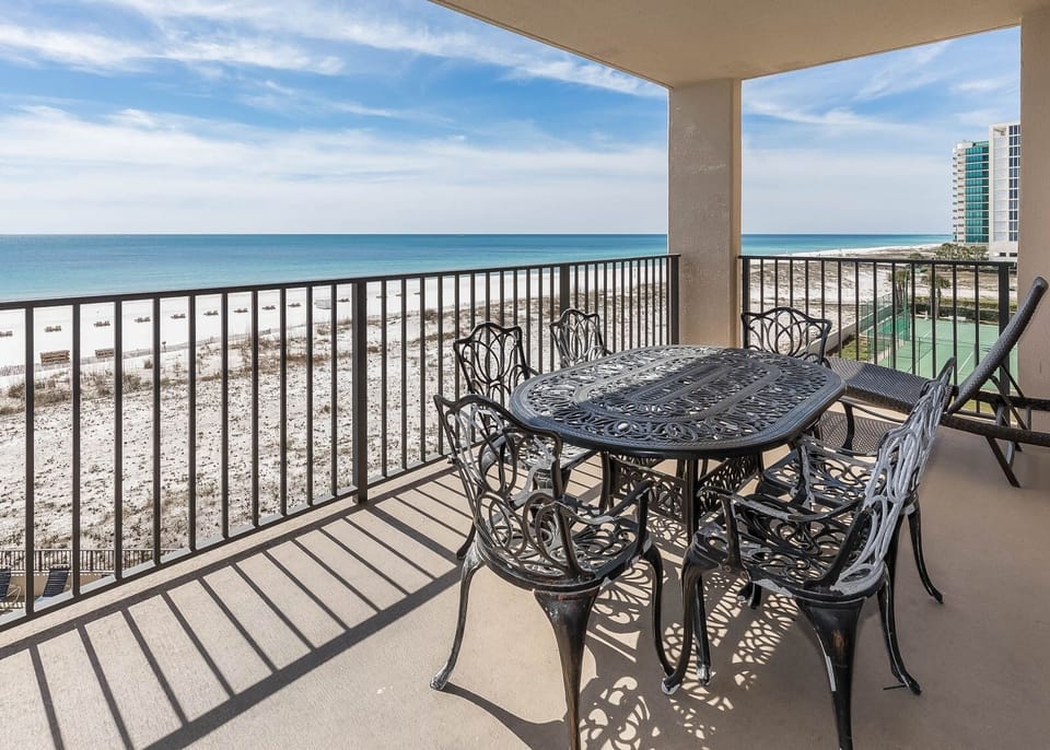 Dine al fresco at the elegant table, enjoying refreshing breezes and stunning beach views of the tranquil waters