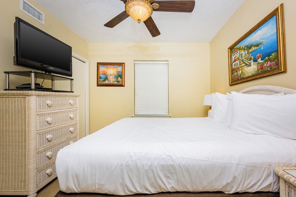 Inviting geust bedroom with a plush queen bed, a TV, and coastal artwork that adds charm to your stay