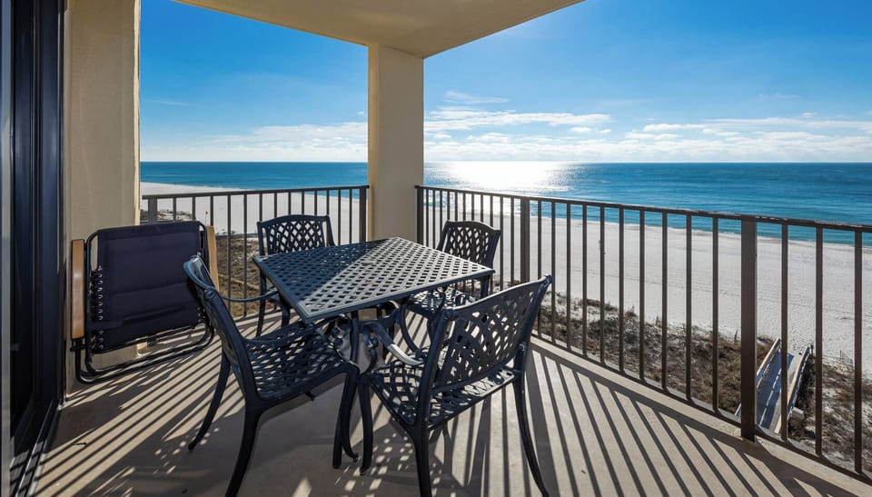 Relax on the balcony with a table and chairs, enjoying the serene beachfront view and sparkling blue waters