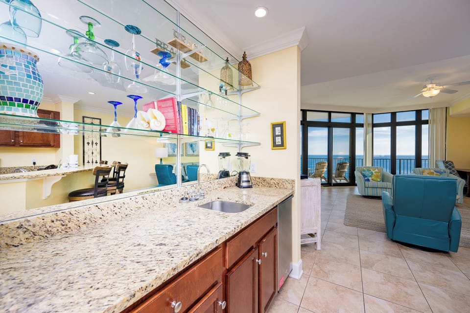 The wet bar features lively glassware, a blender, and a beach view creating an exciting cocktail creation experience