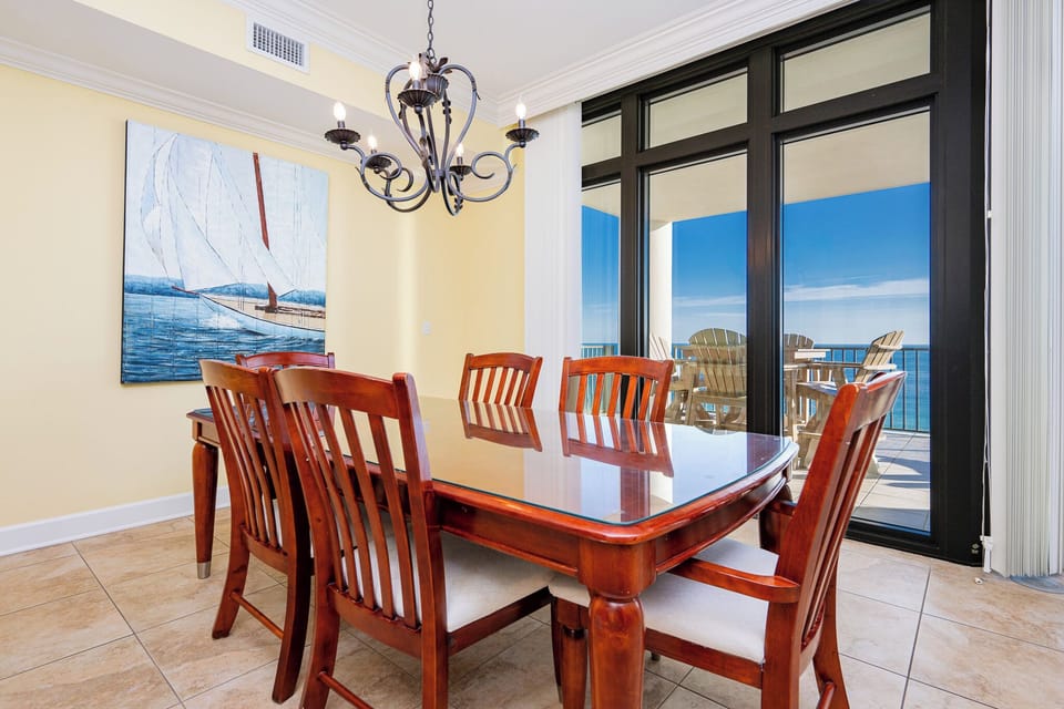 This dining area features a large wooden table and chairs and a nautical vibe for family dining with a beach view