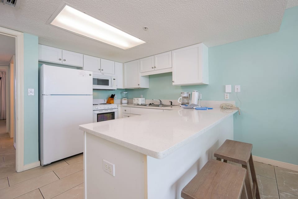 Prepare meals in this functional kitchen with a breakfast bar, essential appliances, and a refreshing color scheme