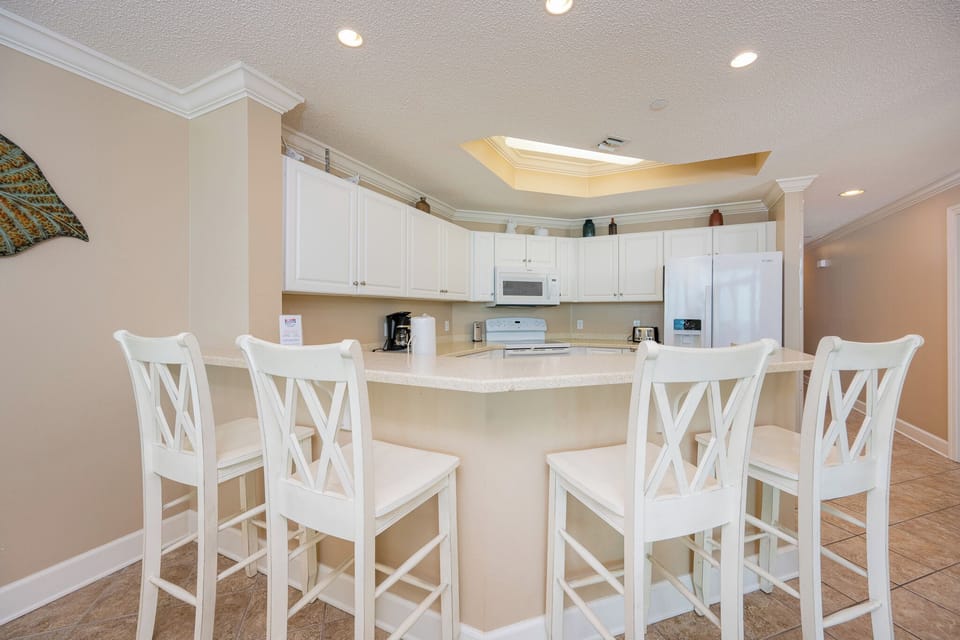 Bright recessed lights warm the kitchen where you sip morning coffee at the breakfast bar stools
