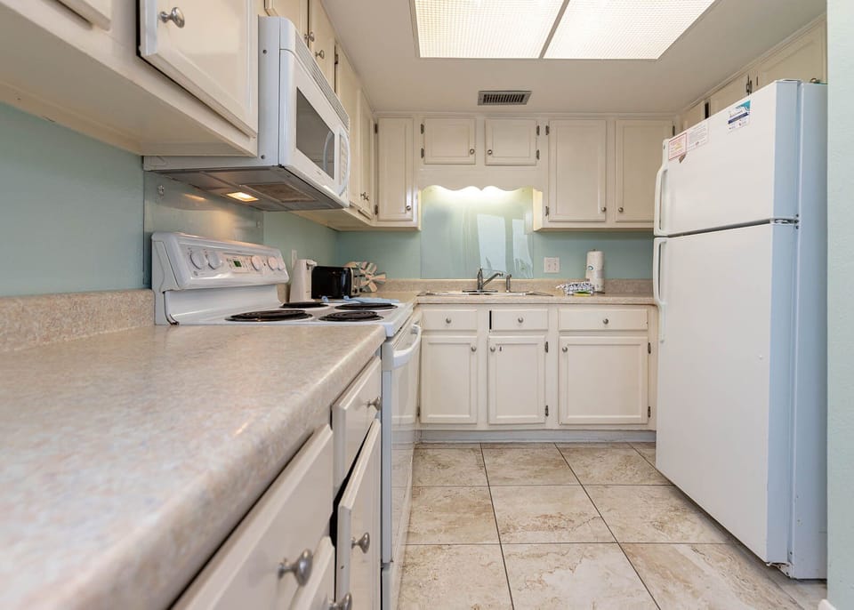 This kitchen features white cabinetry, a spacious countertop, and essential appliances, perfect for your culinary adventures