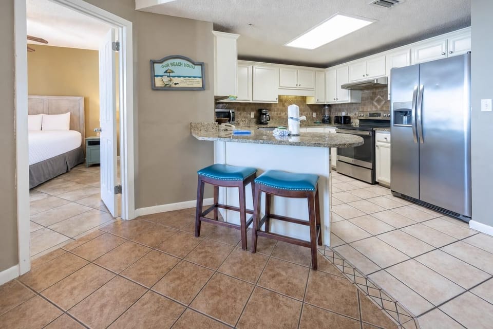 Gather around the breakfast bar with teal stools, enjoying easy access to the kitchen and a cozy master bedroom view