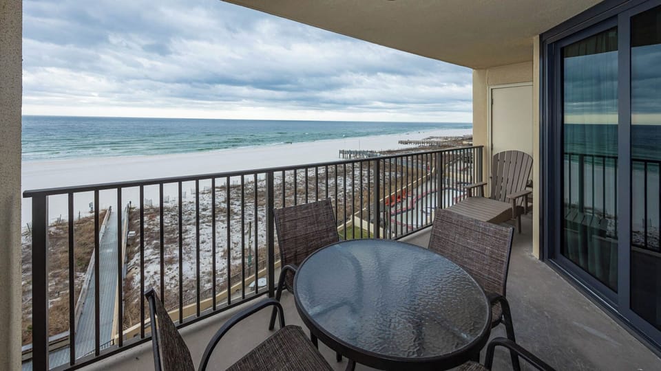 Enjoy a relaxing moment on the balcony with a round table and chairs, overlooking the tranquil beachfront and white sand