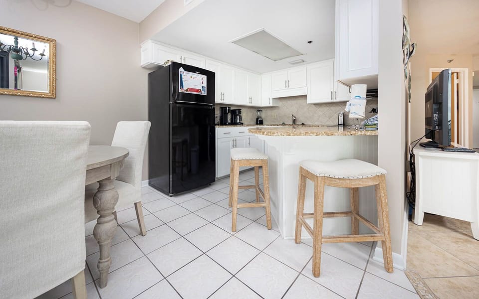 Bright kitchen area featuring white cabinetry, a breakfast bar with stools, coffee station, and a dining area