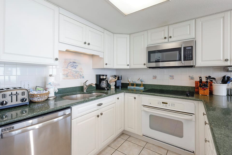The fully-equipped kitchen features white cabinetry, stylish countertops, a Keurig and a coffee maker