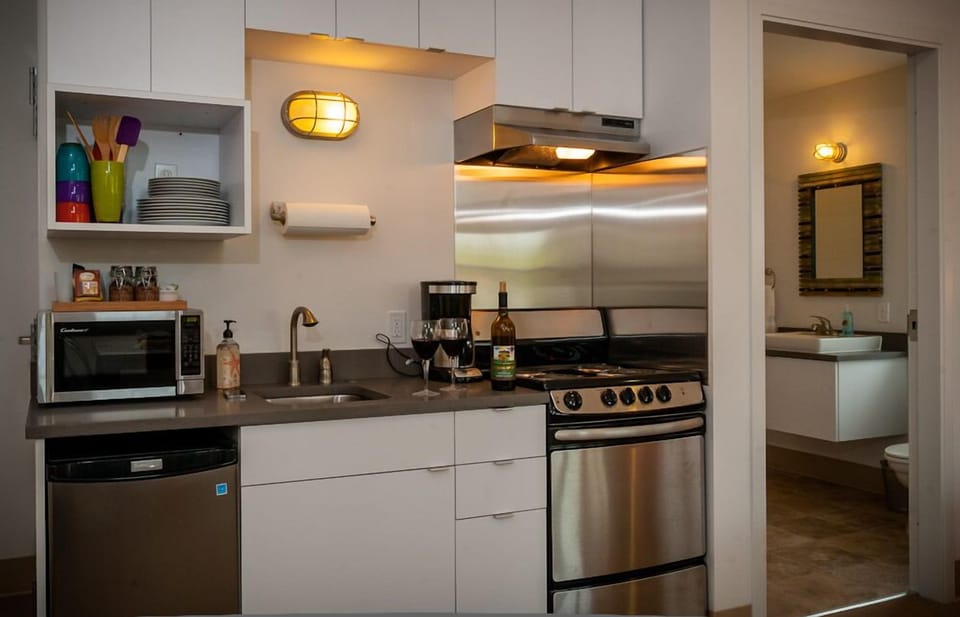 Compact kitchen with range, refrigerator, microwave and coffee maker.