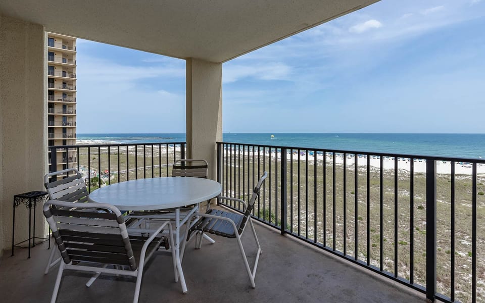 Balcony with a round table and chairs offers a serene view of the gulf and the beach, perfect for relaxing outdoors