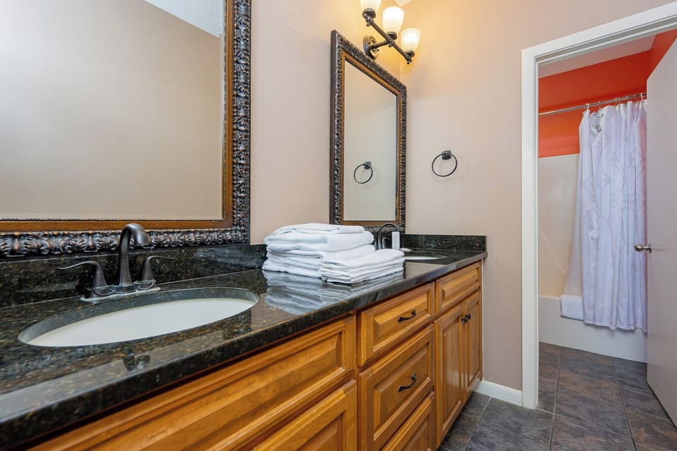Towels stacked on the dual sink vanity welcome you after refreshing showers in the guest suite bathroom