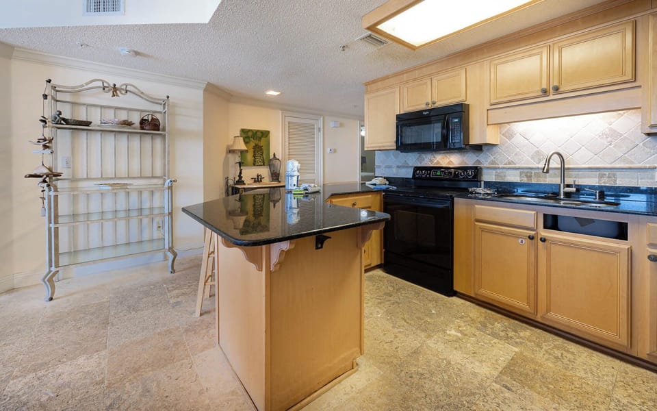 Prepare meals in the spacious kitchen featuring sleek black countertops and ample storage for a comfortable stay