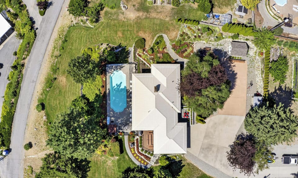 Aerial view showcasing the property's extensive grounds with swimming pool, mature trees, and beautiful landscape creating a peaceful retreat setting.