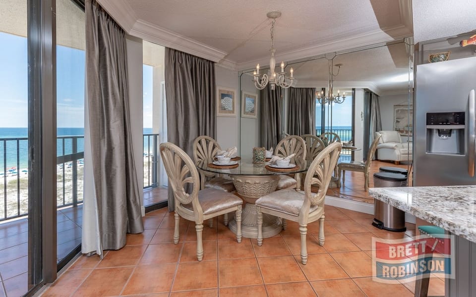 Dine at the elegant table with beach views, surrounded by soft curtains and stylish decor for a relaxing meal