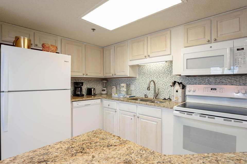Bright kitchen features light cabinetry, granite countertops, and modern appliances, creating a welcoming space for meal prep