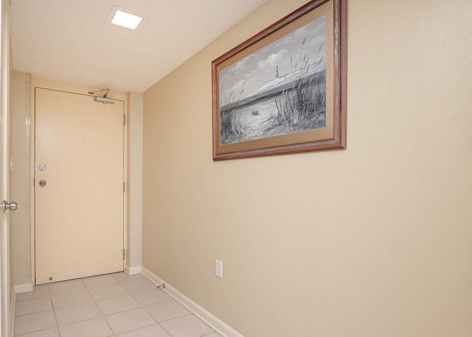 Welcoming entryway featuring a neutral color palette, tile flooring, and a framed coastal artwork enhancing the atmosphere
