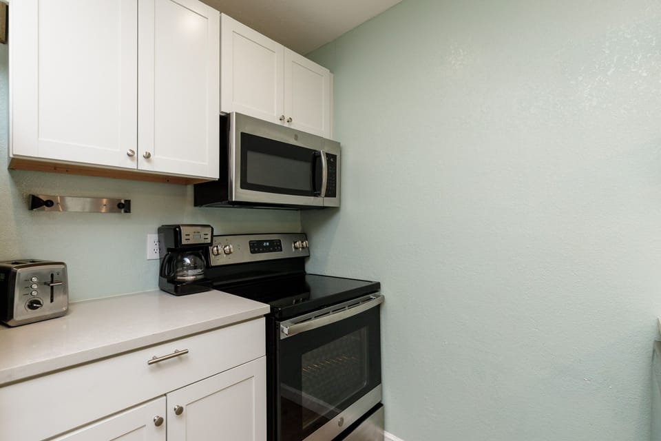 Your fully equipped kitchen features crisp white cabinets, stainless steel appliances, and a bright, welcoming atmosphere for cooking memorable meals.