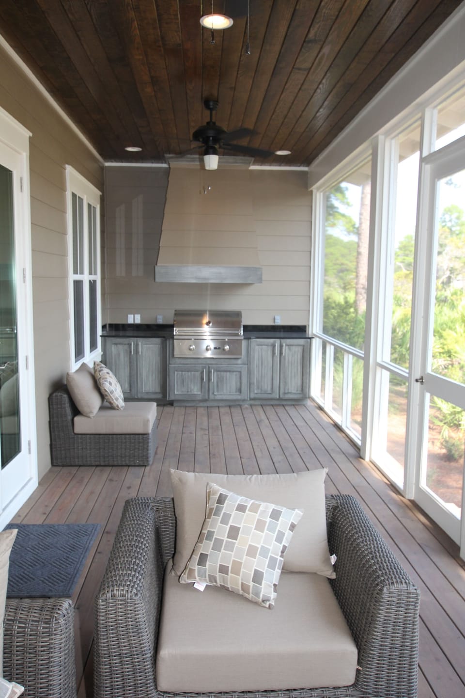Back screen porch with table seating area and lounge area with TV on other side
