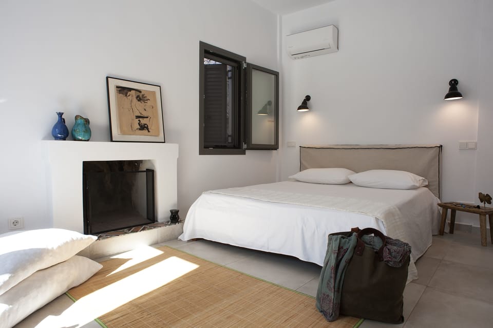 The room features a double bed, wood and concrete furniture that evoke serenity
