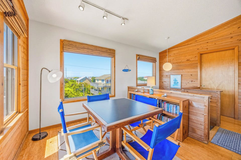Gather around this sunny dining space with vibrant blue seating and warm wood accents, where natural light fills the room and neighborhood views inspire your day.