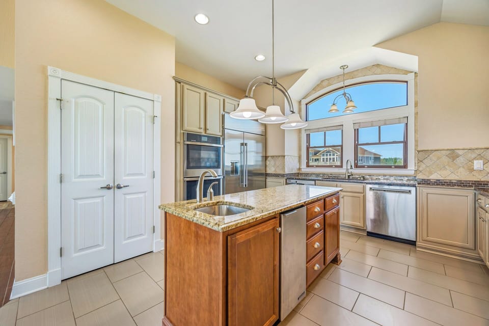 Step into your beautifully appointed kitchen, where warm tones and granite countertops create an inviting space. Sunlight streams through arched windows as you prepare meals at the spacious island, surrounded by modern appliances and thoughtful details des