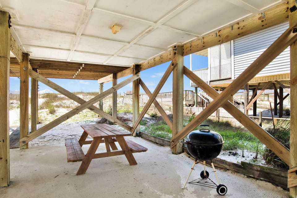 The carport has a picnic table and BBQ grill