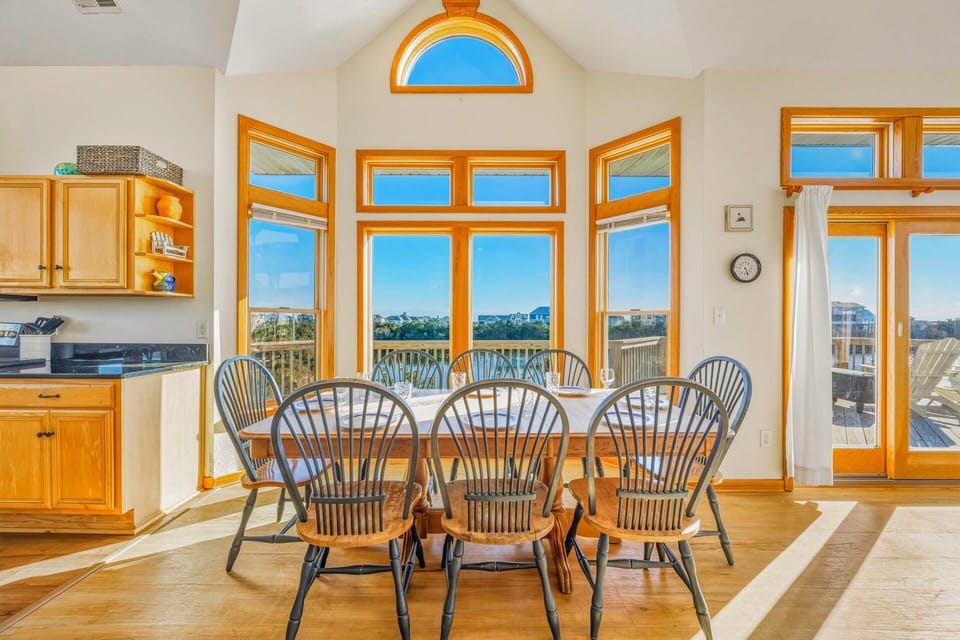 Gather around this sunny dining table where natural light pours through soaring windows, creating the perfect spot for memorable meals with loved ones.